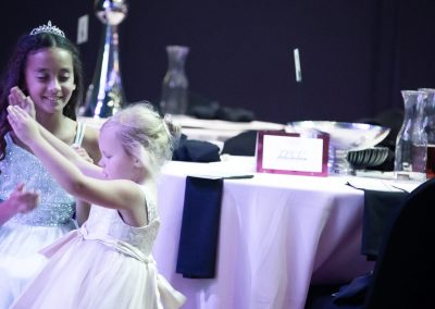 Two young girls wearing sparkly dresses dance