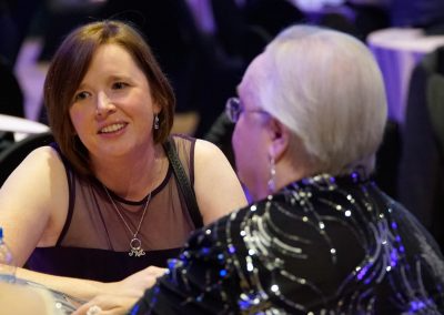 A middle-aged woman with short hair talks to an older woman wearing a sparkly shirt