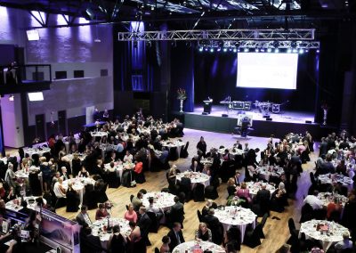 Guests seated at tables in a banquet hall at a breast cancer awareness gala.