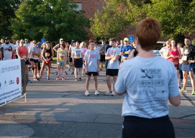 A woman talks to a crowd of runners before a breast cancer awareness race begins.