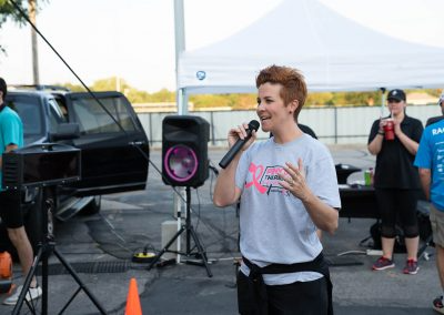 A breast cancer survivor talks into a microphone at a fundraising event