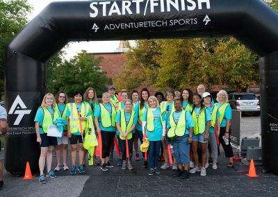 A group of volunteers wearing bright yellow vests at a breast cancer awareness race.