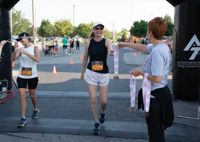 A woman wearing a black tank top and white gym shorts receives her metal for running in a race