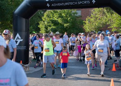 A crowd of people walking through the finish line at a fundraiser race