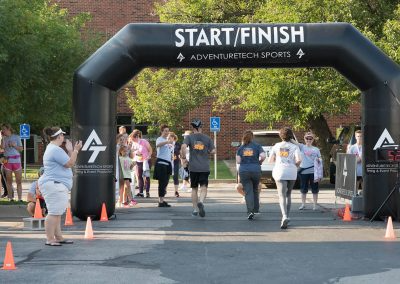 A man and two women are handed medals as they cross the finish line at a fundraiser race