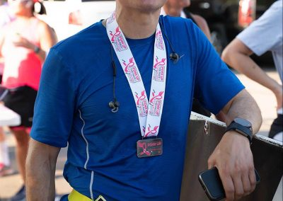 An older male runner leans against fence after finishing race