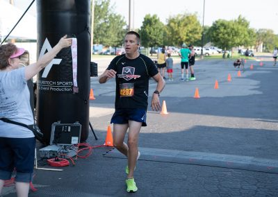 A middle-aged man runs across the finish line and receives his medal