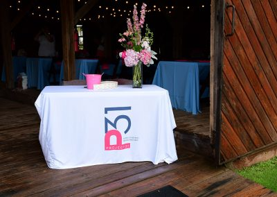 A raffle table with a branded table cloth and vase with pink flowers