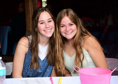 Two teenage girls with long brown hair smile for a photo at a P31 brunch event