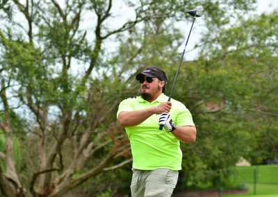 A man wearing a bright green polo swinging a golf club