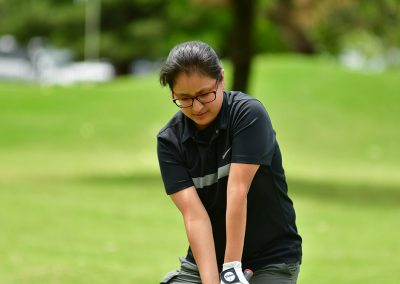 A teenager wearing black glasses and playing golf