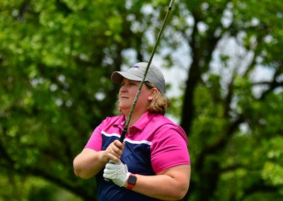 A woman with short hair holding her golf club in the air