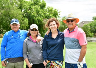 Two older couples smile for a photo while playing golf at a breast cancer awareness golf tournament