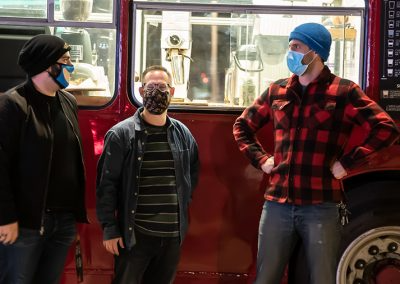 Three men standing by red bus