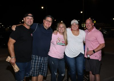 Two middle-aged women smile for a photo with three middle-aged men