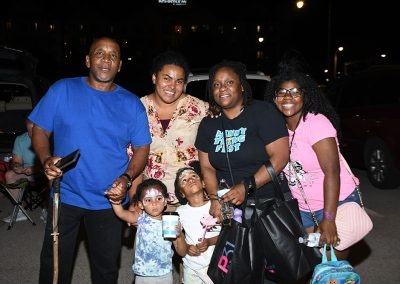 A family of six smile for a photo while holding bags and water bottles