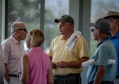 Four older men wearing golf attire talk in a group