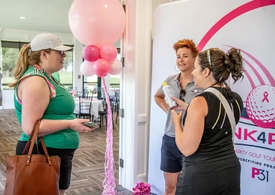 Three women talk to one another at a golf tournament to benefit breast cancer