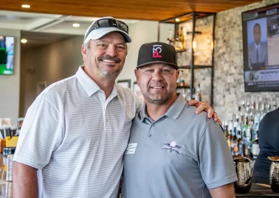 Two men wearing golf polos and hats