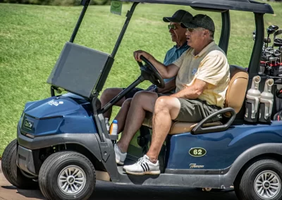 Two older men driving a golf cart