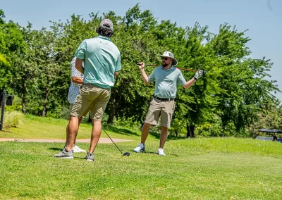 Three men talk while playing golf