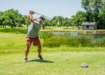 A middle-aged man wearing red shorts swings golf club