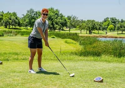 A middle-aged woman with short hair prepares to hit golf ball