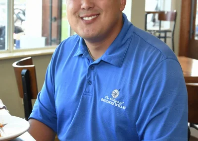 Man wearing a village of Baytowne Wharf sits at a table indoors