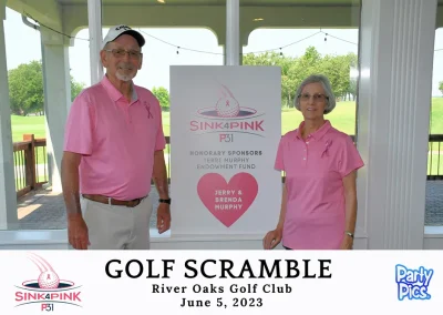 Jerry and Brenda Murphy, both in pink, in front of their honorary sponsor sign