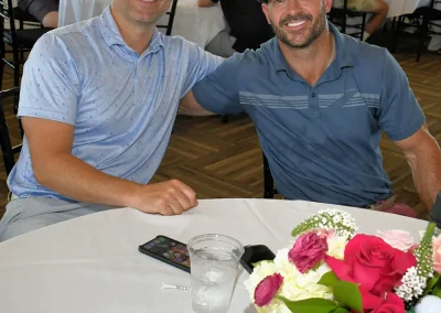 Two men in blue shirts sitting at a table with a white cloth