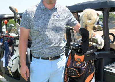 Man is a hat with a set of cubs and beaver club cover in front of a golf cart