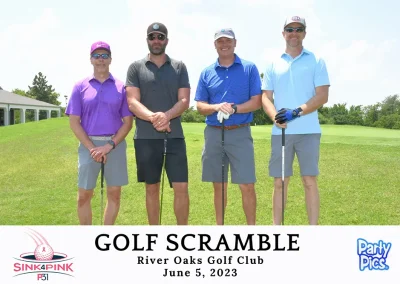 Four men outdoors with golf clubs: one in purple; one in gray, one in dark blue; one in light blue