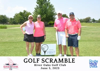 Two women and two men wearing pink shirts in front of a PNT sign.