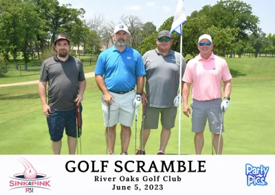 Four men pose by the hole of a golf course with a golf club each. Two in gray, one in blue, and one in pink