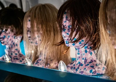 A row of wigs on mannequin heads sitting on a blue shelf