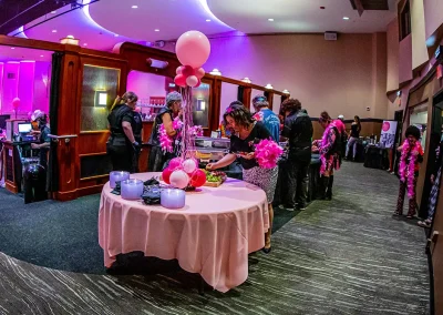 Woman in black shirt and leopard skirt picking up grapes off of appetizer table at breast cancer awareness event