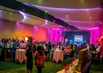 Room filled with guests wearing costumes for breast cancer awareness event