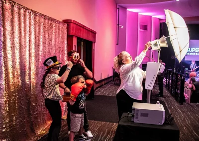 A middle-aged father poses at a photo booth with his daughter and young son wearing props