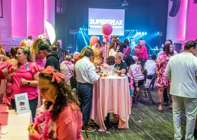 A crowd of adults mingle together at a breast cancer awareness event