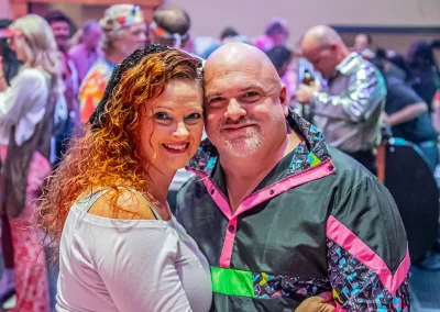 A middle-aged woman with red hair smiles for a photo with a middle-aged man wearing a neon jacket