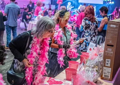 Older woman wearing glasses looks at prizes while a woman in a costume is holding and reading a small sign