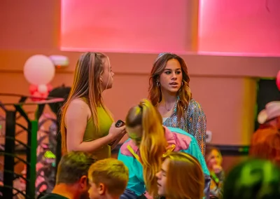 Two younger women in dresses chat at an event