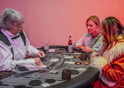 A younger woman and a middle-aged woman play card games at a table with a dealer