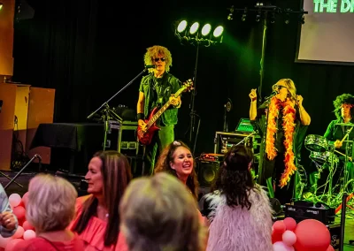 A female singer and male guitarist sing together on stage in front of a crowd