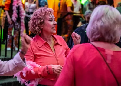 An curly-haired woman talks with other woman at an event