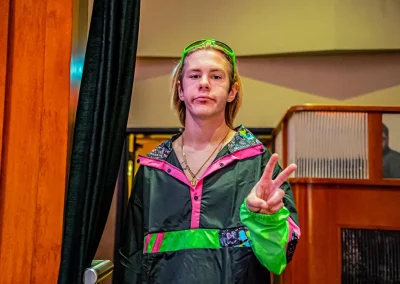 Young man wearing neon jumpsuit makes a peace sign