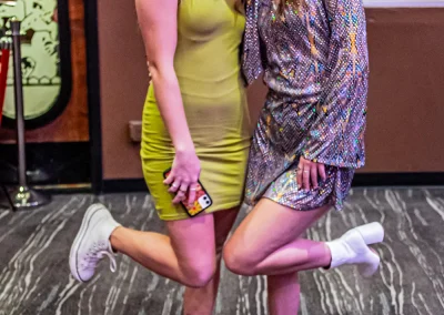 Two young teenage girls wearing semi-formal dresses smile for a photo together