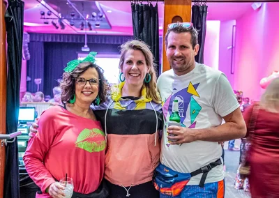 Two middle-aged women smile and pose for a photo with a middle-aged man holding a drink