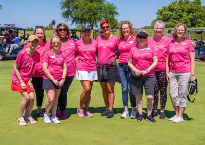 The Project31 team stands together for a group photo on the Sink4Pink golf course. Each woman is wearing a pink t-shirt that says "Survivor."