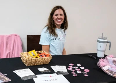 A woman from Restore PT sits at a booth table at the survivorship expo.